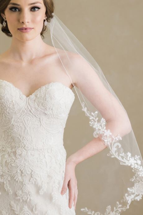 Model wearing fitted lace dress paired with floral veil